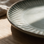 Macro detail of the fine parallel ribs running around the rim of a porcelain plate.