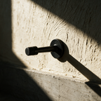 The wall-mounted stop alone projecting from a textured plaster wall in raking light.