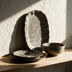 The oval platter propped upright on an oak shelf with a plate and bowl stacked in front.