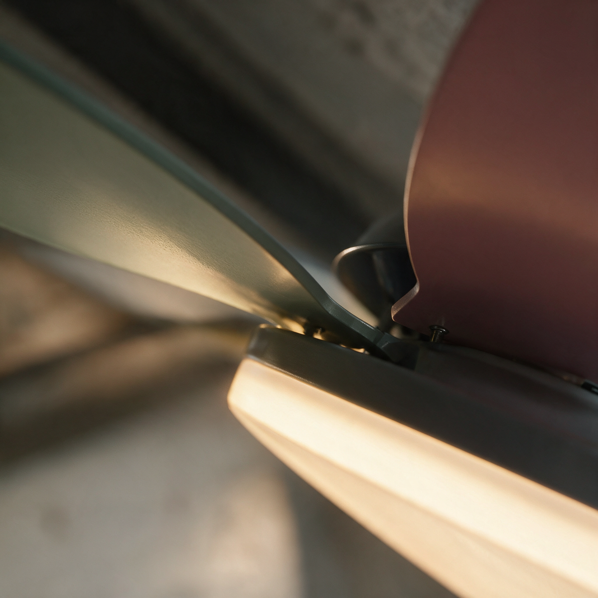 Close-up of a sage blade root meeting the round central housing beside the lit diffuser.