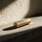 A single knurled brass handle lying on a concrete slab in hard raking light.