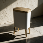 The bin alone on a concrete floor with its four brass legs casting long shadows.