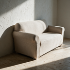 The covered two-seater standing alone against a plaster wall in hard raking sunlight.