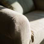 Macro detail of the cross-hatch weave stretching over the curved front edge of a sofa arm.