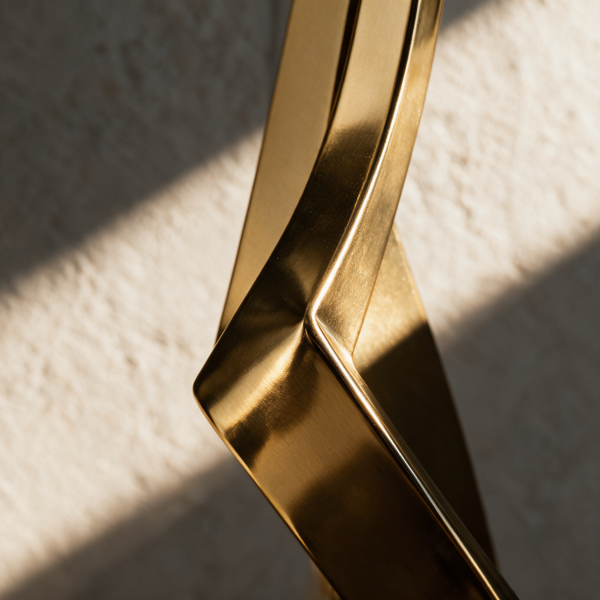 Macro close-up of a hard crease where two flat gold segments of the folded body meet.