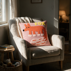 Pink fox embroidered cushion on a linen armchair in a child's reading corner