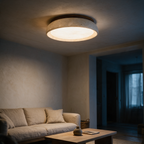 Vesper travertine flush mount lit above a linen sofa at dusk