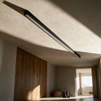 The unlit black bar flush to a plaster ceiling in raking light