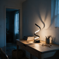 Vane spiral lamp lit on an oak desk at dusk