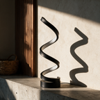 The unlit black helix in raking light against a plaster wall