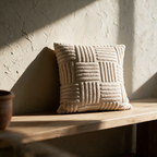 The ribbed tufted cushion standing alone on an oak bench against a plaster wall in raking sunlight.