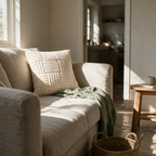 Cream ribbed tufted cushion propped in the corner of an oatmeal linen sofa in afternoon light.