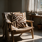 Brown geometric tufted cushion on a rush-seated oak armchair in a sunlit reading corner.