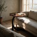 Scalloped dark wood C-table pulled over a linen sofa cushion with a mug and open book on top