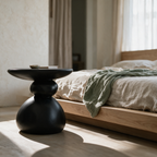 Low view of the pebble stack table beside a bed showing its wide base
