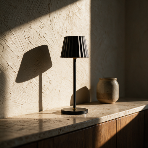 Unlit table lamp on a travertine sideboard with raking sunlight picking out the fluted shade.