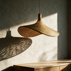 Unlit rattan pendant casting a rippled shadow across a textured plaster wall in low afternoon sun.