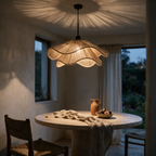 Wide frilled jute pendant lit above a round travertine dining table at dusk.