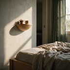 Half-moon oak floating ledge on a bedroom wall holding a trailing plant and a cup