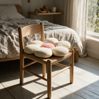 Flower-shaped corduroy cushion resting on a small rush-seated chair in a sunlit bedroom corner.
