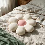 Overhead view of the flower-shaped cushion lying on a rumpled linen bed beside an open book.