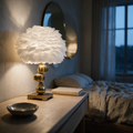 Feather shade lamp on a brass pebble stem glowing on a dressing table at dusk.