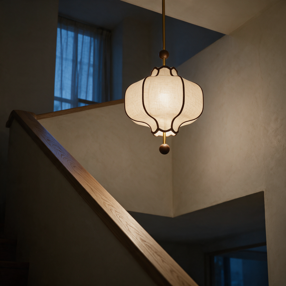 Side profile of the lit lantern hanging in a stairwell with a timber handrail in the foreground.