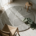 Overhead view of the whole circular rug on floorboards with a chair and a folded throw.