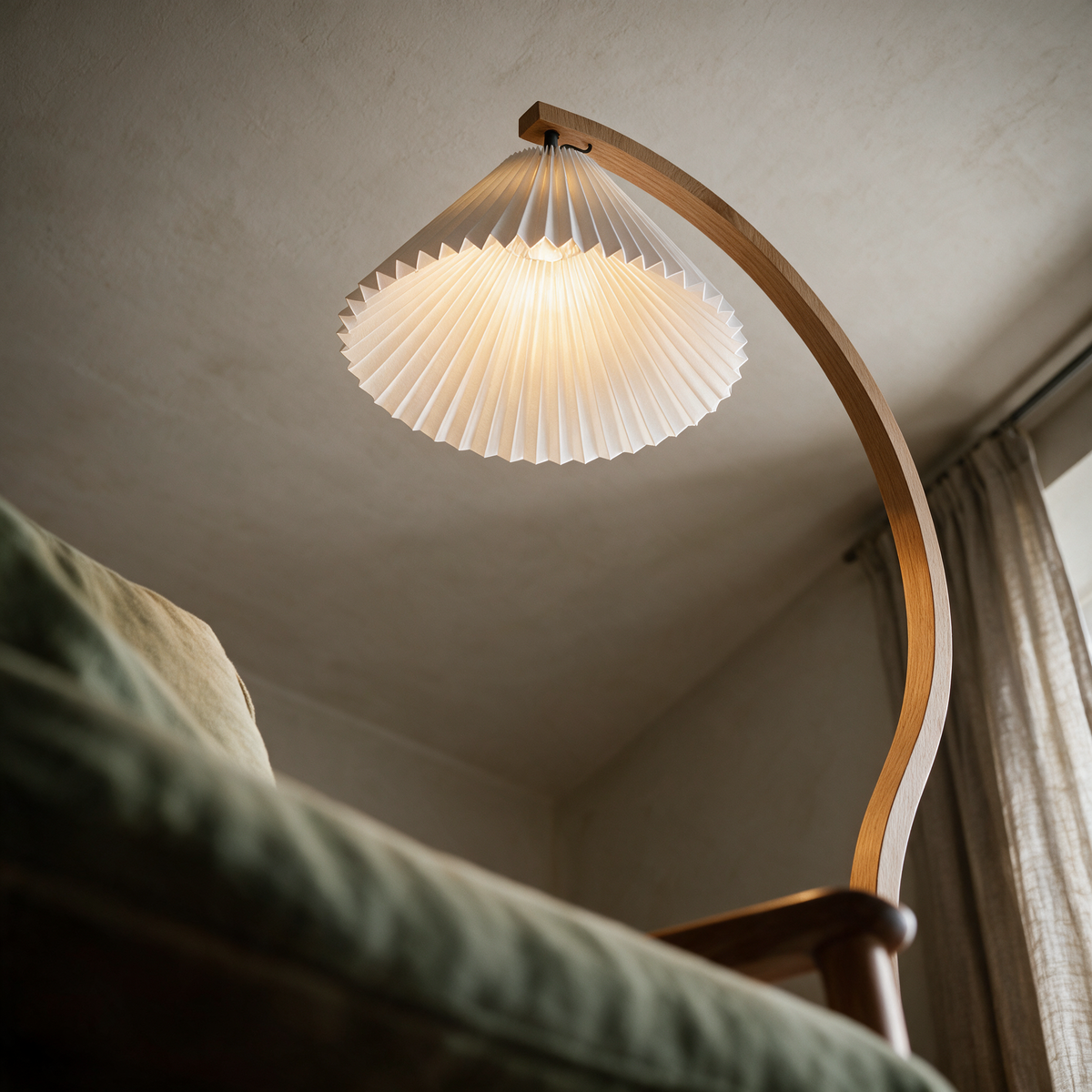 Looking up from a reading chair at the glowing pleated cone and the curving arc.