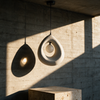 Unlit teardrop resin pendant casting a sharp shadow across a board-formed concrete wall.