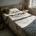 Blue and cream mandala print cotton throw spread across a low oak bed in afternoon light.