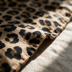 Macro detail of black rosettes printed on the tan woven fabric beside a seamed edge.