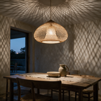 Double-layer woven rattan lattice dome pendant lit above a long dining table at dusk.