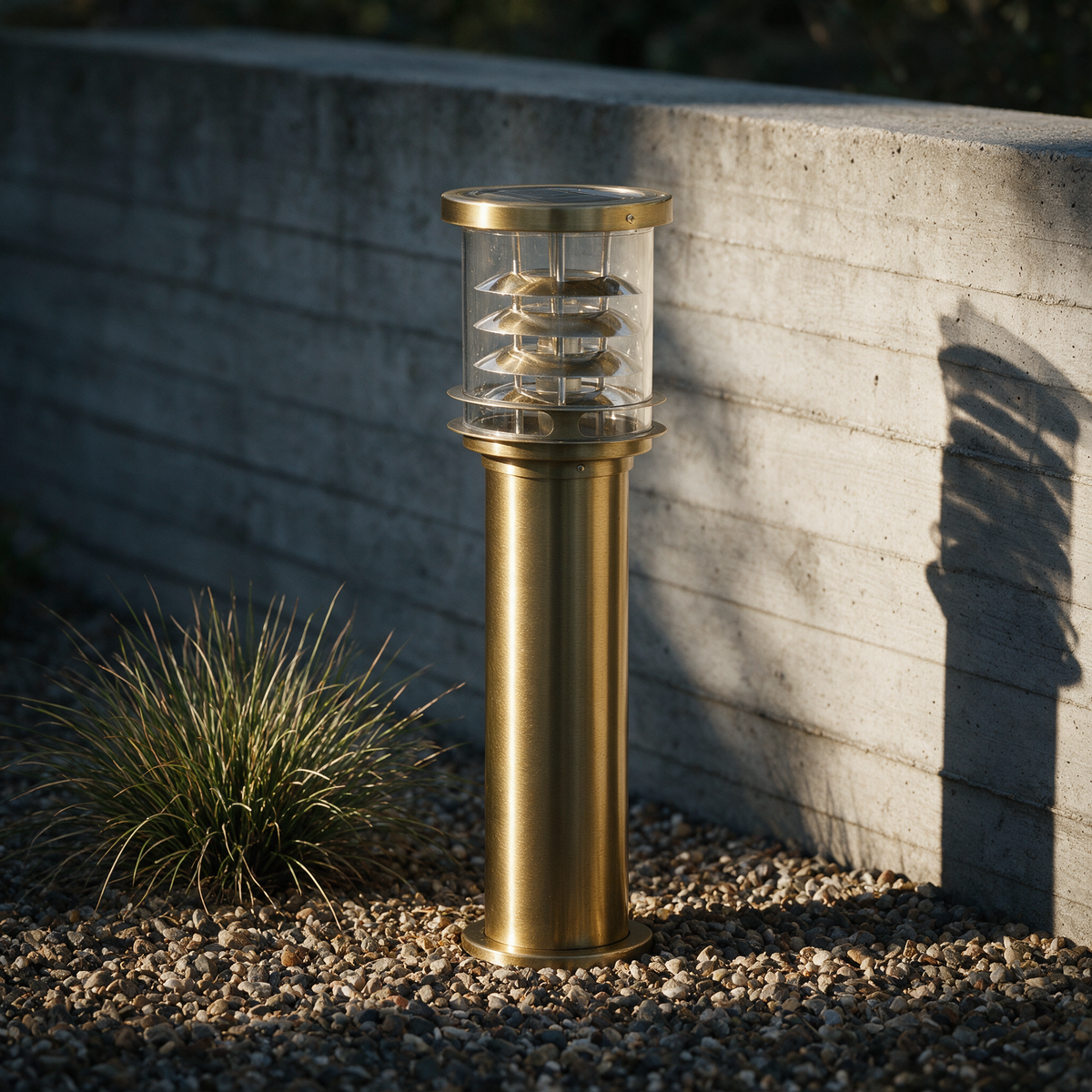 Unlit brass bollard on gravel with sunlight picking out each louvre tier.