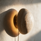 Macro close-up of the stone rim and the gap where warm light spills onto the plaster behind.