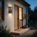 Dark grey hollow-frame outdoor wall light glowing beside a timber front door at dusk.