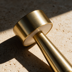 Close up of the smooth brushed brass head and stem of a compact cordless table lamp
