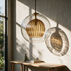 Clear glass globe pendant with a ribbed amber inner shade hanging beside a sunlit plaster wall