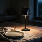 Cordless table lamp with a glossy black fluted shade lighting a dining table at dusk