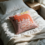 Pink tufted fox cushion resting on a white linen bed in morning light